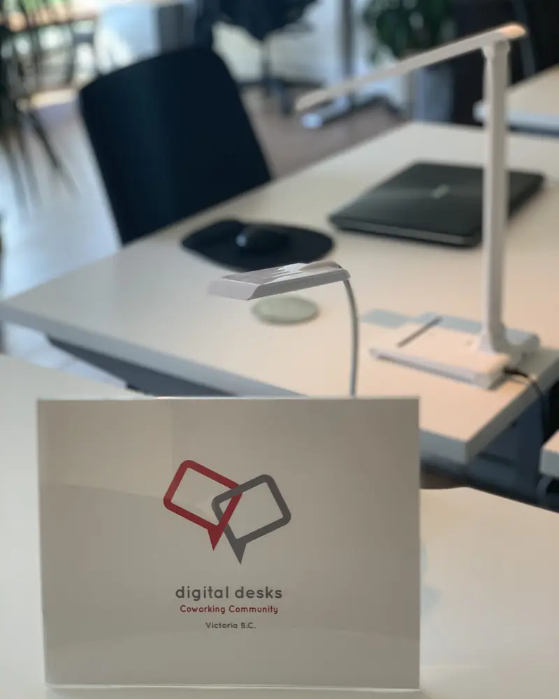 A Digital Desks sit/stand desk with a desk lamp and the Digital Desks welcome card